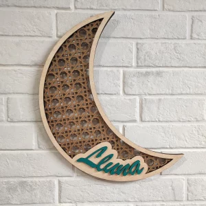 Media luna de dos capas de madera de 3mm cada una, la capa inferior es simulado al ratán y la capa superior cortada solo la silueta de la luna en madera con el nombre personalizado de color verde turquesa encima